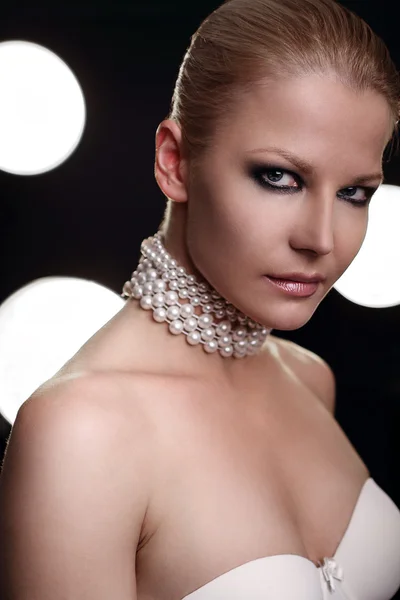 Fashion portrait of a beautiful young sexy woman in early 30th with blue smoky eyes make up wearing pearls — Stock Photo, Image