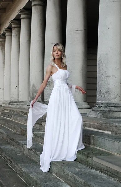 Young beautiful blonde bride portrait standing on a staircase of a classical building — Stock Photo, Image