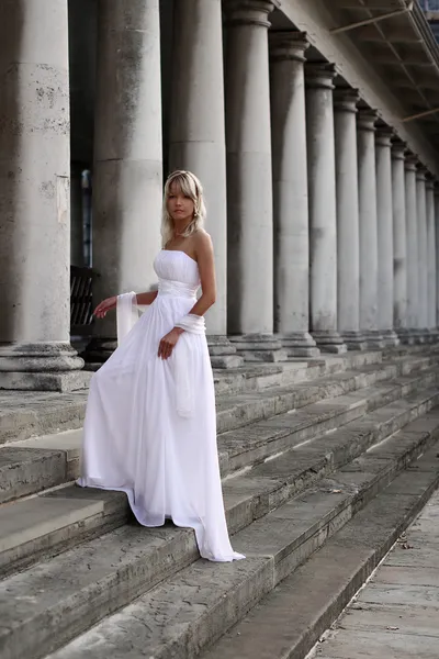 Young beautiful blonde bride portrait standing on a staircase of a classical building — Stock Photo, Image