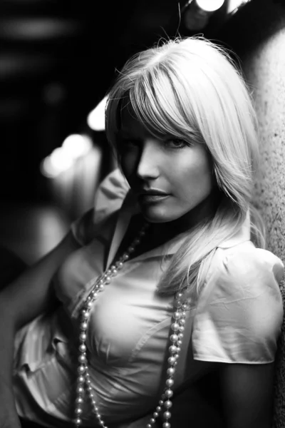 Jonge blonde model meisje dicht omhoog portret in haar vroege 30s of 20s op zoek recht in een wit overhemd met een witte parels met flare verlichting op de achtergrond in een tunnel — Stockfoto