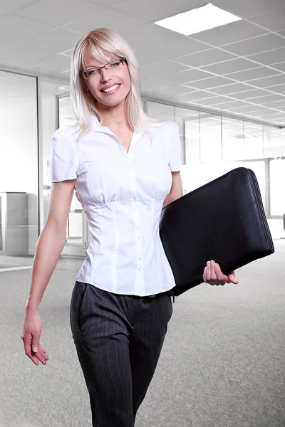 Jovens mulheres de negócios atraentes sorrindo usando óculos segurando uma pasta em um ambiente de escritório andando — Fotografia de Stock