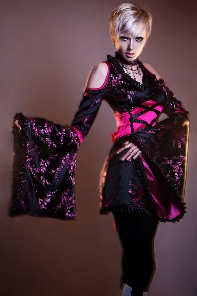 Inusual joven modelo rubia de moda posando con un extraño vestido negro rojo estudio disparo rayo mixto larga velocidad del obturador — Foto de Stock