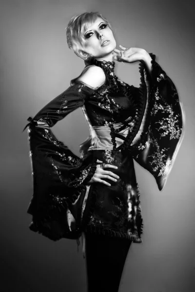 Inusual joven modelo rubia de moda posando con un extraño vestido negro rojo estudio disparo rayo mixto larga velocidad del obturador — Foto de Stock