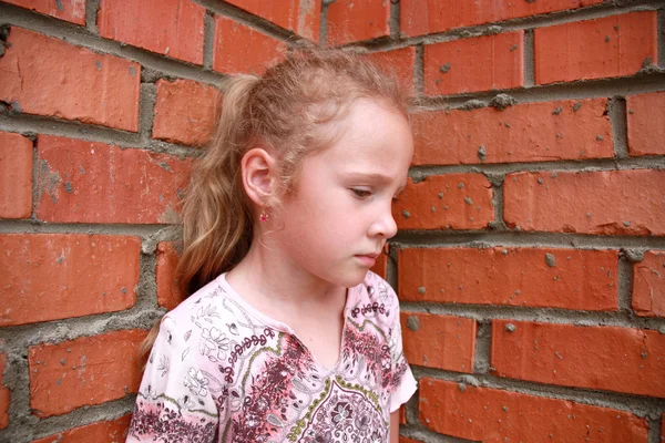 Грустный ребенок с кирпичной стеной — стоковое фото