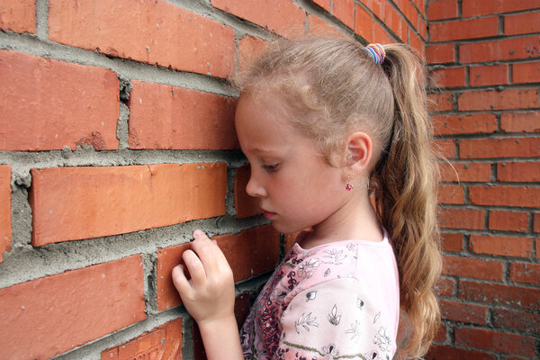 Sad child with a brick wall