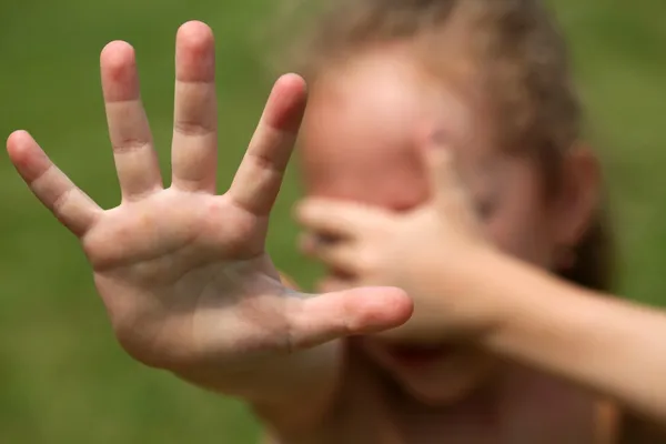 L'enfant refuse, et est couvert les mains — Photo