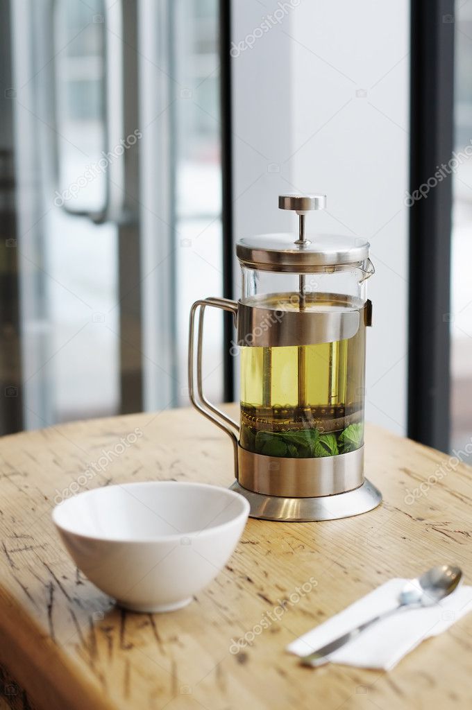 French-press with green tea on the table