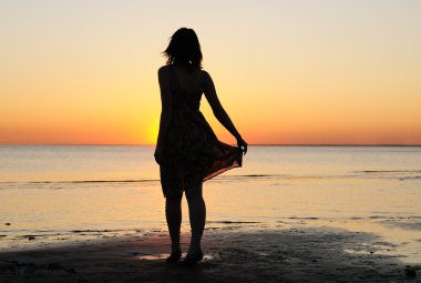 vrouw als silhouet door de zee