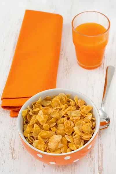 Cornflakes in the bowl with spoon and juice — Stock Photo, Image