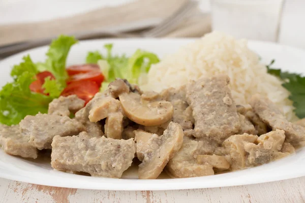 Varkensvlees met champignons, gekookte rijst en salade — Stockfoto