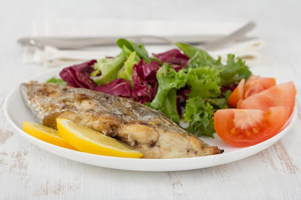 Жареная рыба-меч с салатом на тарелке — стоковое фото