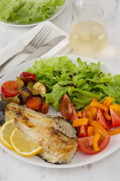Жареная рыба с овощами и салатом — стоковое фото