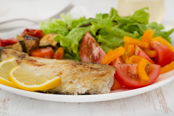 Жареная рыба с овощами и салатом — стоковое фото