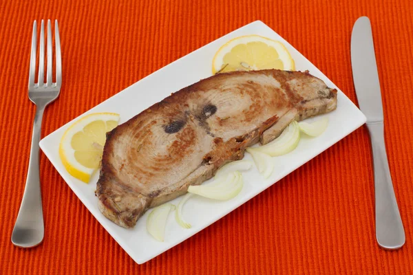Жареный тунец с лимоном и луком на тарелке — стоковое фото