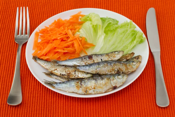 Sardine fritte con lattuga e carota sul piatto — Foto Stock