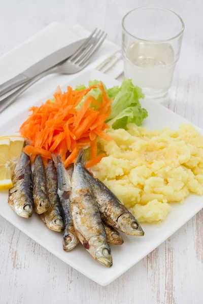 Smažené sardinky se salátem a šťouchané brambory na talíři — Stock fotografie