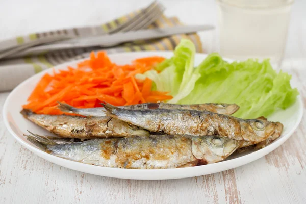 Fried sardines with lettuce and carrot on the plate — Stock Photo, Image