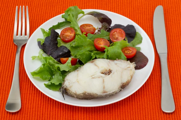 Poisson bouilli avec salade dans une assiette blanche — Photo