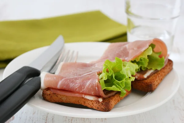 Toasts with prosciutto and lettuce — Stock Photo, Image