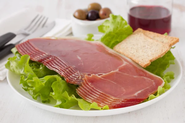 Prosciutto with toasts and glass of red wine — Stock Photo, Image