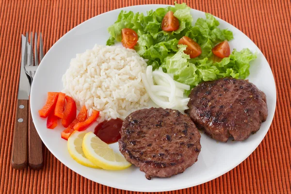 Grilled hamburgers with boiled rice and salad — Stock Photo, Image