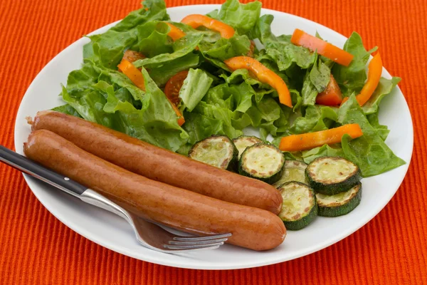Жареные сосиски с салатом и овощами — стоковое фото