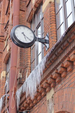 Old clock and Icicles on a brick wal clipart