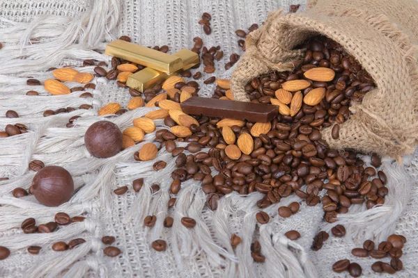 Chocolates surtidos, granos de café y almendras en saco de lona —  Fotos de Stock