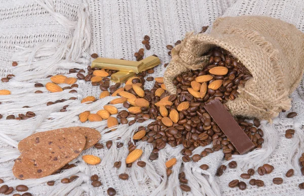 Galletas, chocolates, granos de café y almendras en saco de lona — Foto de Stock