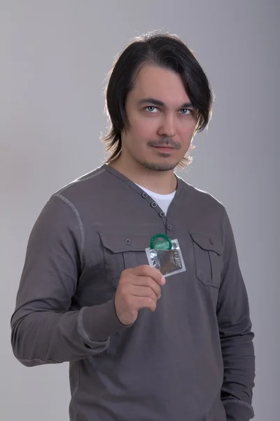 Handsome man holding green condom — Stock Photo, Image