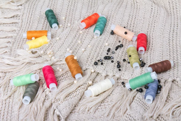 Colorful threads and beads on a fabric background — Stock Photo, Image