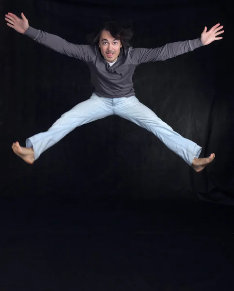 Молодой человек прыгает, на черном фоне — стоковое фото