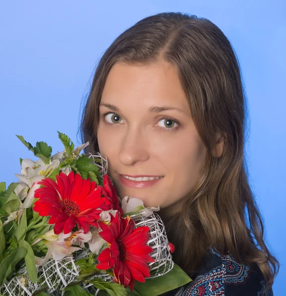 Ung glad kvinna med blommor på blå bakgrund — Stockfoto