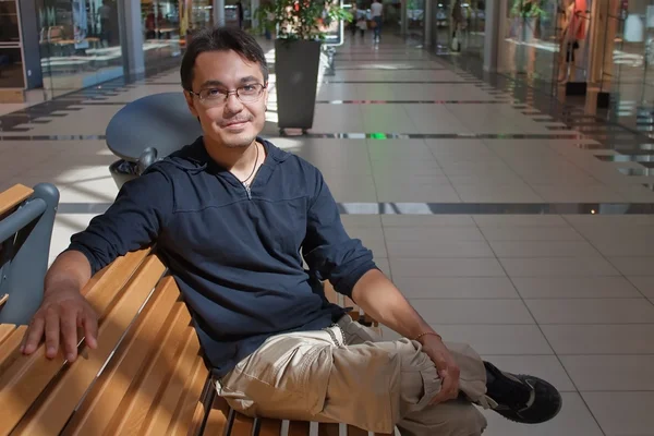 Portrait of young man on bench in mall — Stock Photo, Image