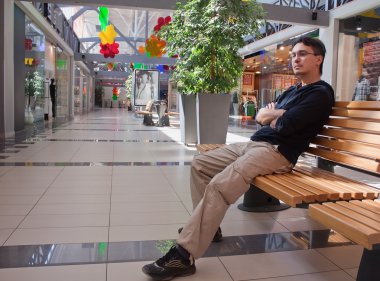alışveriş merkezinde bankta genç adam portresi