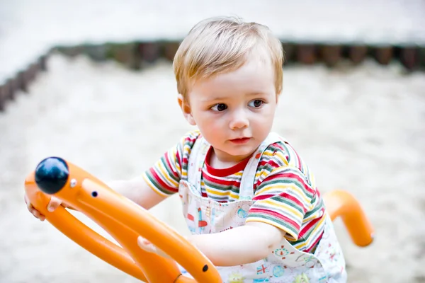 Мальчик, качающийся на качелях в парке на детской площадке — стоковое фото