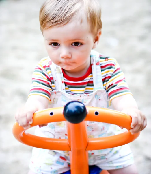 Um retrato de um menino em um balanço em um playground . — Fotografia de Stock