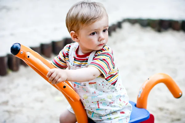 Bonito menino brincando no swing no playground. Verão — Fotografia de Stock