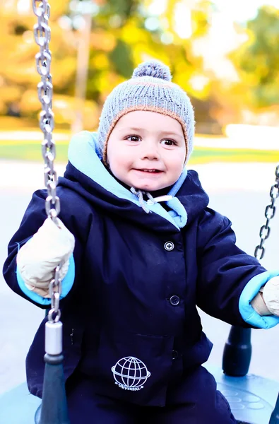 Cute baby boy on swing in autumn park — Stock Photo, Image