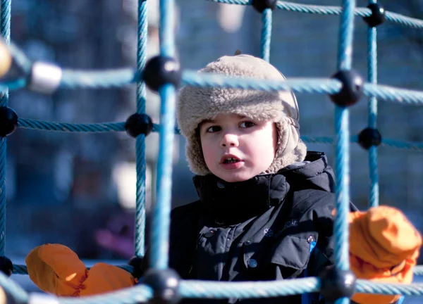 Хлопчик на дитячому майданчику, зимовий час — стокове фото