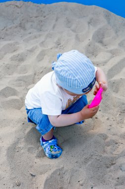 Sandbox içinde küçük bir çocuk. Yaz