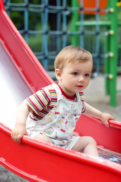 Милий маленький хлопчик спустився з дитячого слайда — стокове фото