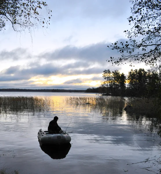 Il pescatore solitario in una barca su un tramonto — Foto Stock