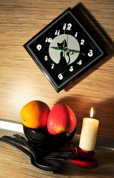 Натюрморт на кухні з апельсином і яблуком проти чорних годин — стокове фото