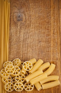 Raw pasta on wood background clipart
