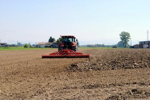 红色拖拉机准备种子在农地土壤 — 图库照片