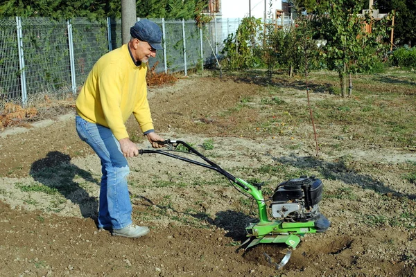 Uomo di mezza età con una Rototiller in giardino — Foto Stock