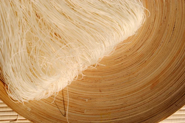 Raw rice needles on a round wooden dish — Stock Photo, Image