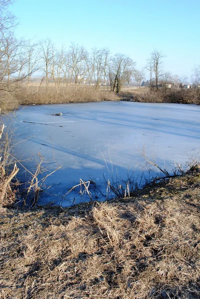 Lago congelado em terras agrícolas em um dia ensolarado — Fotografia de Stock