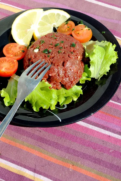 Carne moída crua com verduras em um prato preto — Fotografia de Stock